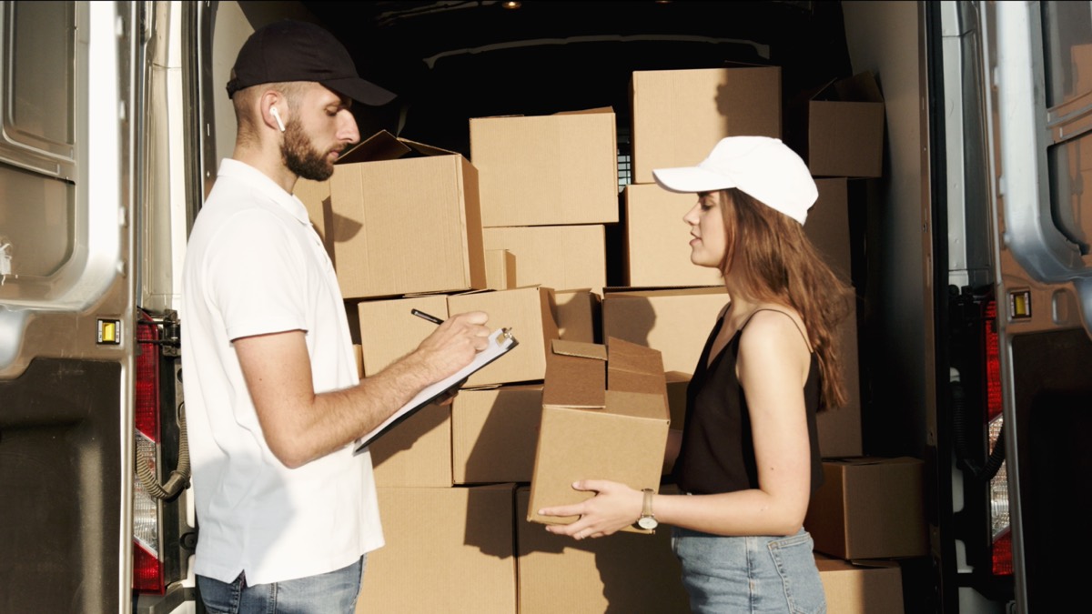 Courier loading grouped business parcels beside a van.
