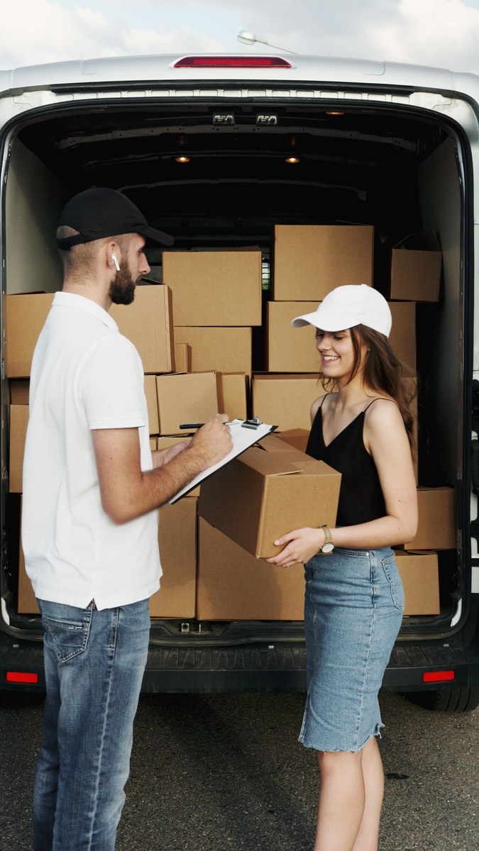 Courier handing over a parcel beside a delivery van.