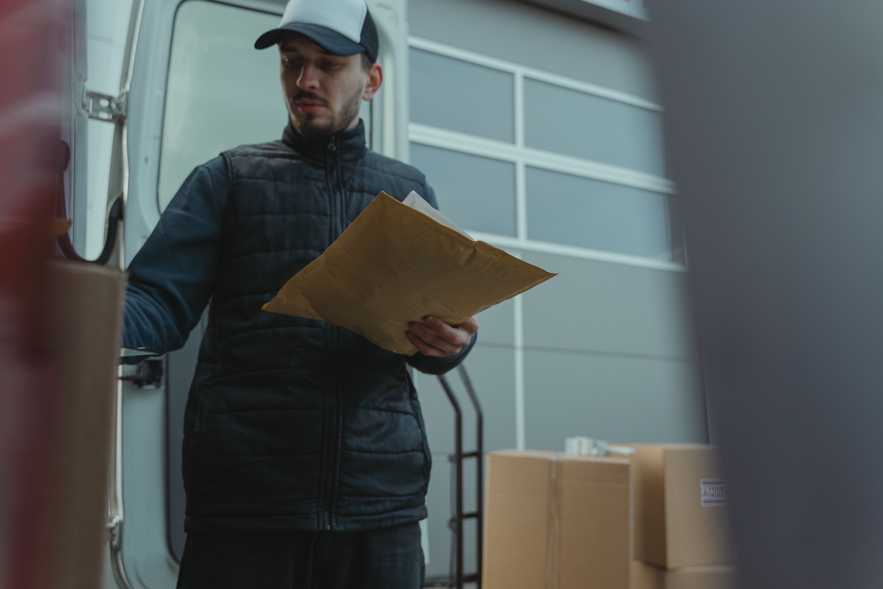 Courier stepping from a delivery van with parcels ready for collection and onward delivery.