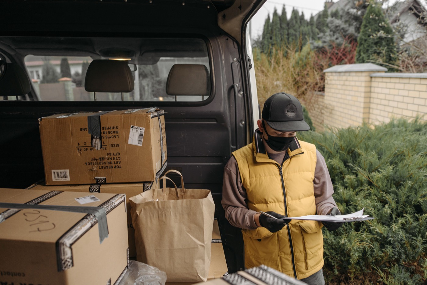 Driver checking delivery paperwork beside parcels inside a van.